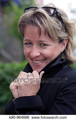Portrait of young caucasian woman with sun glasses and short blond hair, smiling and looking into the camera, holding her hands at the collar, Hamburg, Germany, Europe View Large Photo Image Stock Photograph - Portrait of young caucasian woman with sun glasses and short blond hair, smiling and looking into the camera, holding her hands at the collar, Hamburg, Germany, Europe. Fotosearch