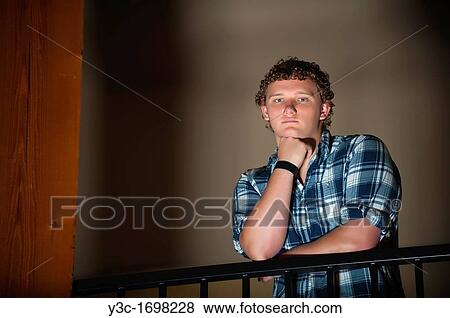 Stock Photo - Portrait of young man standing behind handrail. Fotosearch