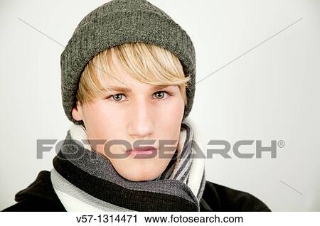 Stock Image - Portrait of young man wearing woollen cap and scarf. Close view.. Fotosearch