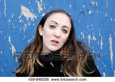 Portrait of young woman against weathered blue background. View Large Photo Image Stock Photo - Portrait of young woman against weathered blue background.. Fotosearch