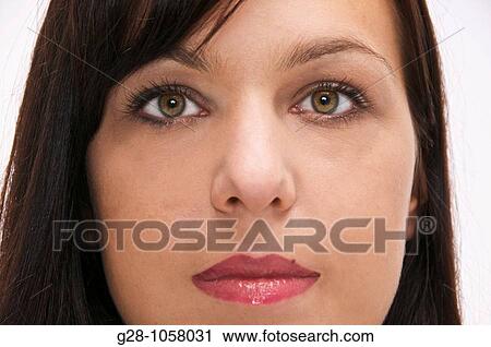 Stock Image - portrait of young woman eyes wide open, facing camera, neutral expression. Fotosearch
