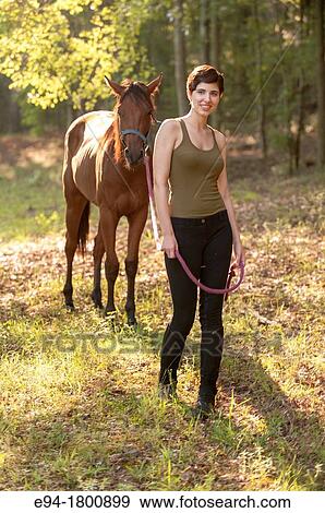 Portrait of young woman in a pasture with a horse View Large Photo Image Stock Photo - Portrait of young woman in a pasture with a horse. Fotosearch