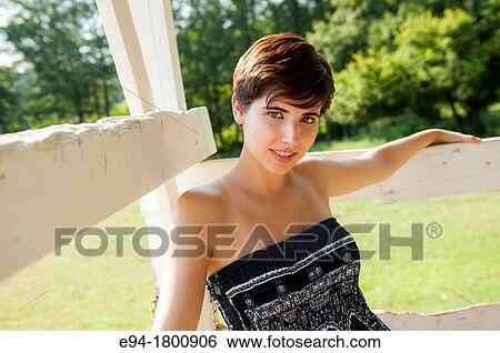 Portrait of young woman leaning on a white fence View Large Photo Image Stock Photograph - Portrait of young woman leaning on a white fence. Fotosearch
