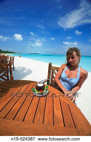 Stock Photo - Portrait of young woman on the beach with cocktail, Maldives, Indian ocean. Fotosearch