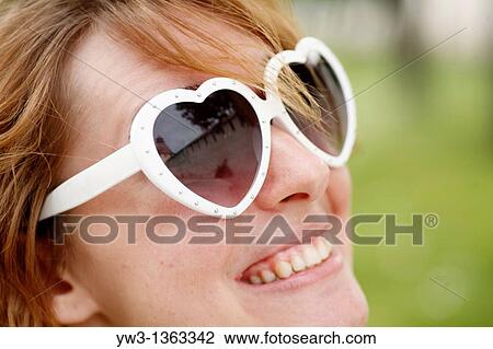 Portrait of young woman outdoors with heart-shaped sunglasses View Large Photo Image Stock Image - Portrait of young woman outdoors with heart-shaped sunglasses. Fotosearch