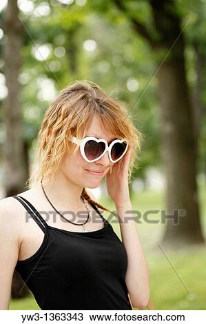 Portrait of young woman outdoors with heart-shaped sunglasses View Large Photo Image Stock Image - Portrait of young woman outdoors with heart-shaped sunglasses. Fotosearch