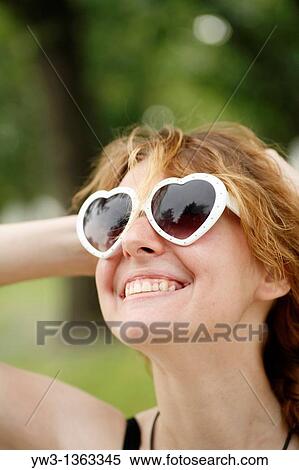 Portrait of young woman outdoors with heart-shaped sunglasses View Large Photo Image Stock Photography - Portrait of young woman outdoors with heart-shaped sunglasses. Fotosearch