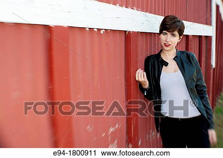 Portrait of young woman standing next to a red wall of a barn View Large Photo Image Stock Image - Portrait of young woman standing next to a red wall of a barn. Fotosearch
