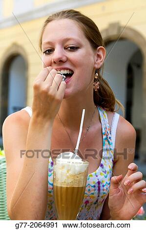 Prague. Czech Republic. Portrait of a young woman smiling sitting in an outdoor restaurant eating an ice cream View Large Photo Image Stock Image - Prague. Czech Republic. Portrait of a young woman smiling sitting in an outdoor restaurant eating an ice cream. Fotosearch
