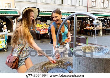 Prague. Czech Republic. Two young women in a market playing with water in a fountain. View Large Photo Image Picture - Prague. Czech Republic. Two young women in a market playing with water in a fountain.. Fotosearch