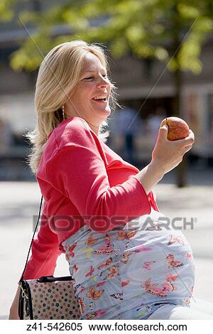 Stock Photography - Pregant woman is enjoying eating an apple.. Fotosearch