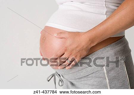 Picture - Pregnant belly with hands. Fotosearch