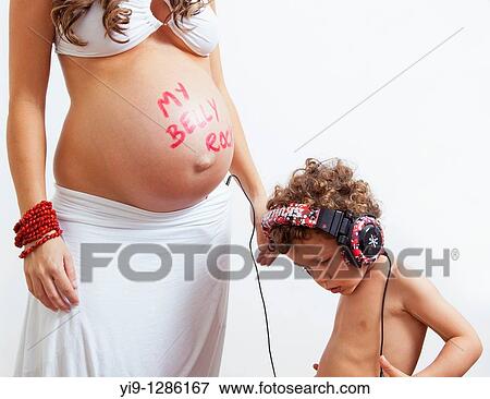 Stock Photo - Pregnant woman and child listening to music with baby. Fotosearch