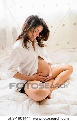 Picture - Pregnant woman caressing her belly. Fotosearch