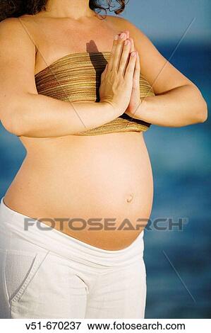 Pregnant woman doing yoga by the sea View Large Photo Image Stock Photo - Pregnant woman doing yoga by the sea. Fotosearch
