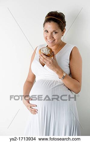 Pregnant woman eating a cinnamon roll View Large Photo Image Picture - Pregnant woman eating a cinnamon roll. Fotosearch
