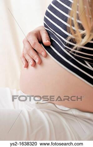 Pregnant woman holding a hand on her belly View Large Photo Image Stock Image - Pregnant woman holding a hand on her belly. Fotosearch