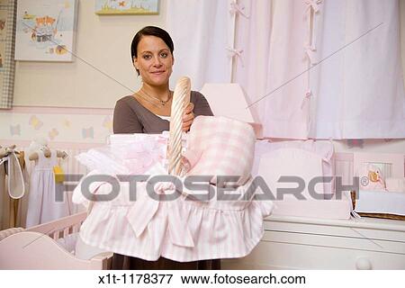 Stock Photo - Pregnant woman holding basket of baby clothes.. Fotosearch