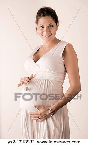 Stock Image - Pregnant woman holding hand with miniature disco ball on her stomach. Fotosearch