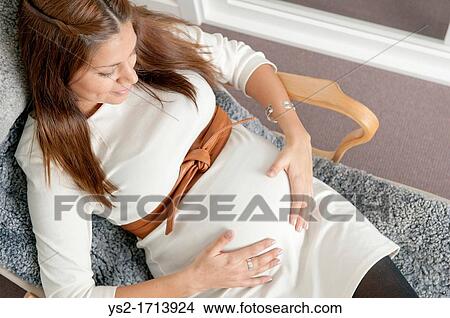 Pregnant woman holding hands on her stomach View Large Photo Image Picture - Pregnant woman holding hands on her stomach. Fotosearch