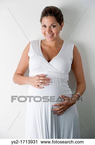 Stock Image - Pregnant woman holding hands on her stomach. Fotosearch
