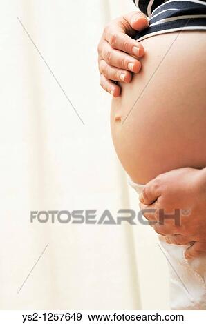 Pregnant woman holding hands on her belly View Large Photo Image Stock Photo - Pregnant woman holding hands on her belly. Fotosearch