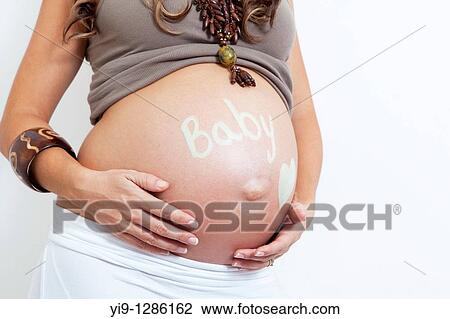 Pregnant woman holding her swollen abdomen View Large Photo Image Stock Image - Pregnant woman holding her swollen abdomen. Fotosearch