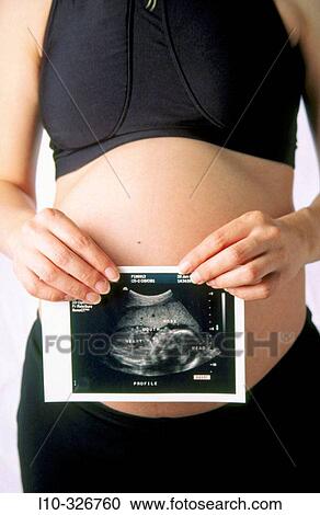 Pregnant woman holds her first ultrasound taken a few month before View Large Photo Image Stock Image - Pregnant woman holds her first ultrasound taken a few month before. Fotosearch
