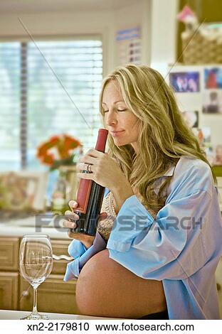 Pregnant woman is tempted by wine in her kitchen. View Large Photo Image Stock Image - Pregnant woman is tempted by wine in her kitchen.. Fotosearch