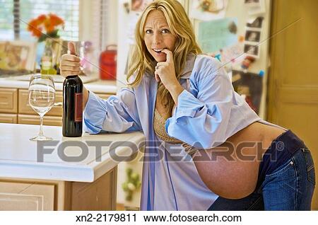 Pregnant woman is tempted by wine in her kitchen. View Large Photo Image Stock Image - Pregnant woman is tempted by wine in her kitchen.. Fotosearch