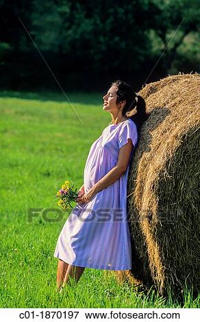 Pregnant woman leaning back against a bale of hay View Large Photo Image Stock Photo - Pregnant woman leaning back against a bale of hay. Fotosearch