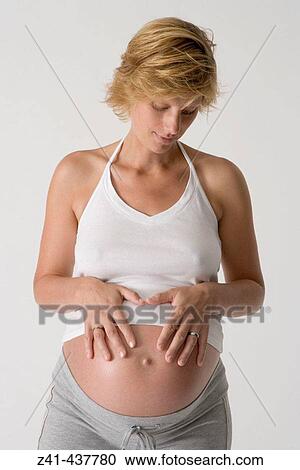 Stock Image - Pregnant woman looking at her belly. Fotosearch