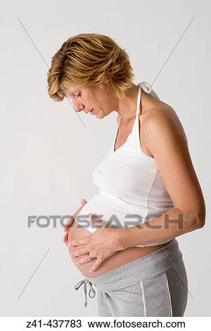 Stock Image - Pregnant woman looking at her belly. Fotosearch