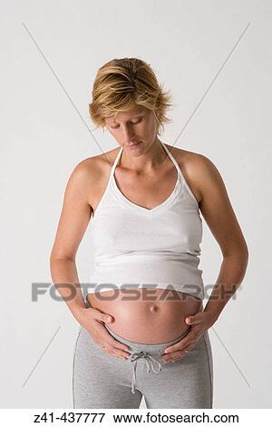 Pregnant woman looking at her belly View Large Photo Image Stock Photo - Pregnant woman looking at her belly. Fotosearch
