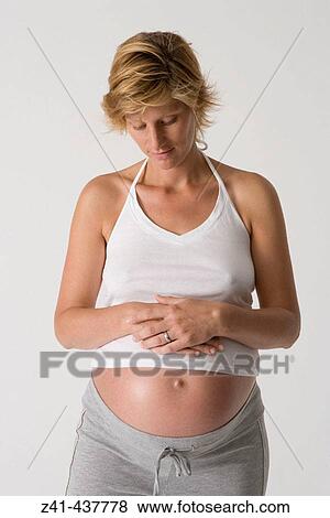 Stock Photo - Pregnant woman looking at her belly. Fotosearch