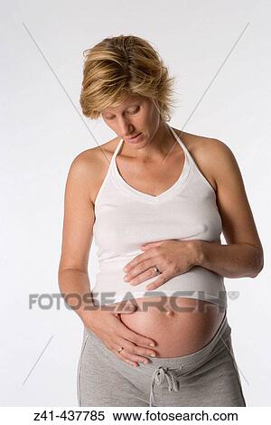Stock Photography - Pregnant woman looking at her belly. Fotosearch