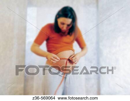 Picture - Pregnant woman measuring her belly. Fotosearch