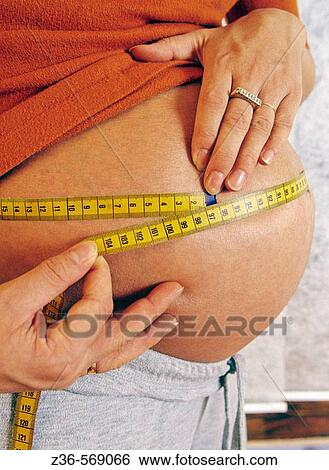 Pregnant woman measuring her belly View Large Photo Image Stock Photograph - Pregnant woman measuring her belly. Fotosearch