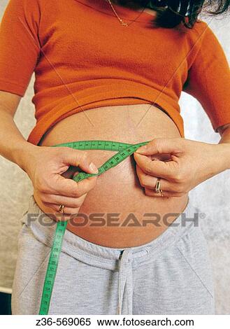 Stock Photography - Pregnant woman measuring her belly. Fotosearch