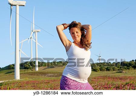 Picture - Pregnant woman relaxing in field. Fotosearch