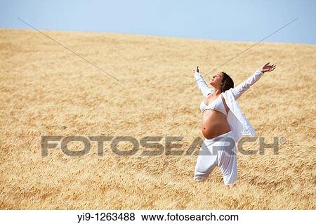 Stock Photo - Pregnant woman relaxing in field. Fotosearch