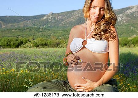 Pregnant woman relaxing in field View Large Photo Image Stock Photo - Pregnant woman relaxing in field. Fotosearch