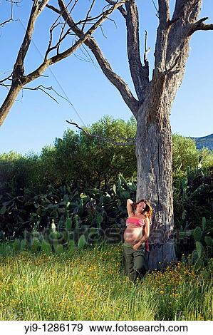 Stock Photo - Pregnant woman relaxing in field. Fotosearch