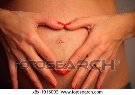 Pregnant woman showing heart on her bell View Large Photo Image Stock Image - Pregnant woman showing heart on her bell. Fotosearch