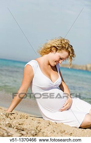 Pregnant woman sitting at the beach View Large Photo Image Stock Photograph - Pregnant woman sitting at the beach. Fotosearch