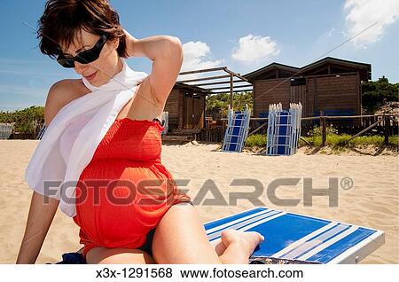 Pregnant woman sitting down on the beach by the sea View Large Photo Image Stock Photo - Pregnant woman sitting down on the beach by the sea. Fotosearch
