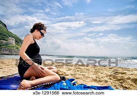 Pregnant woman sitting down on the beach by the sea View Large Photo Image Stock Photograph - Pregnant woman sitting down on the beach by the sea. Fotosearch