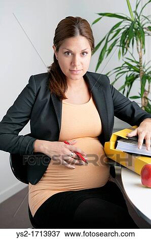 Pregnant woman sitting in an office View Large Photo Image Stock Photo - Pregnant woman sitting in an office. Fotosearch