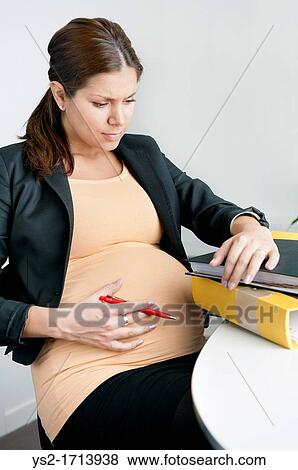 Pregnant woman sitting in an office looking troubled View Large Photo Image Stock Photo - Pregnant woman sitting in an office looking troubled. Fotosearch