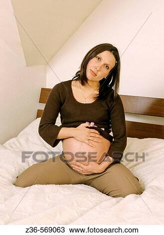 Pregnant woman sitting on bed View Large Photo Image Stock Image - Pregnant woman sitting on bed. Fotosearch